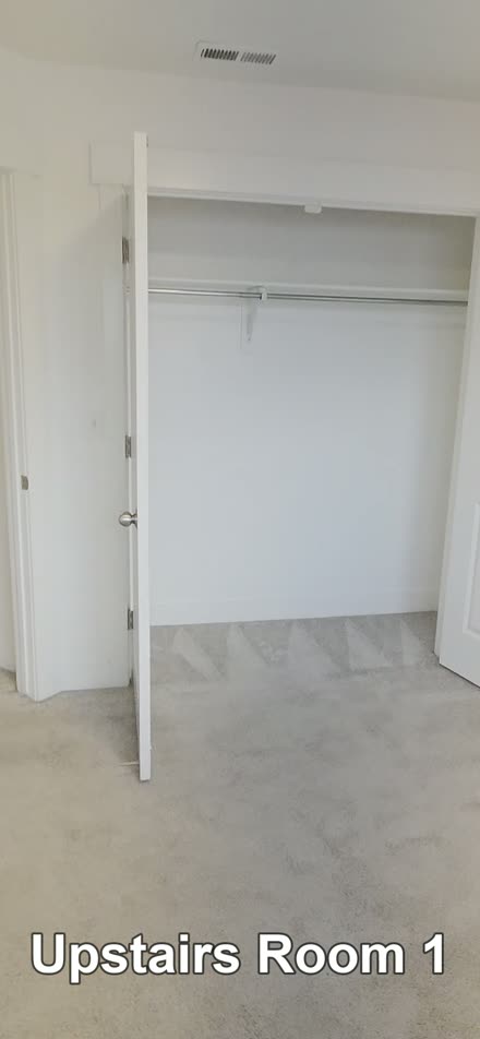 Video frame of a vacant bedroom with the on-screen label Upstairs Room 1